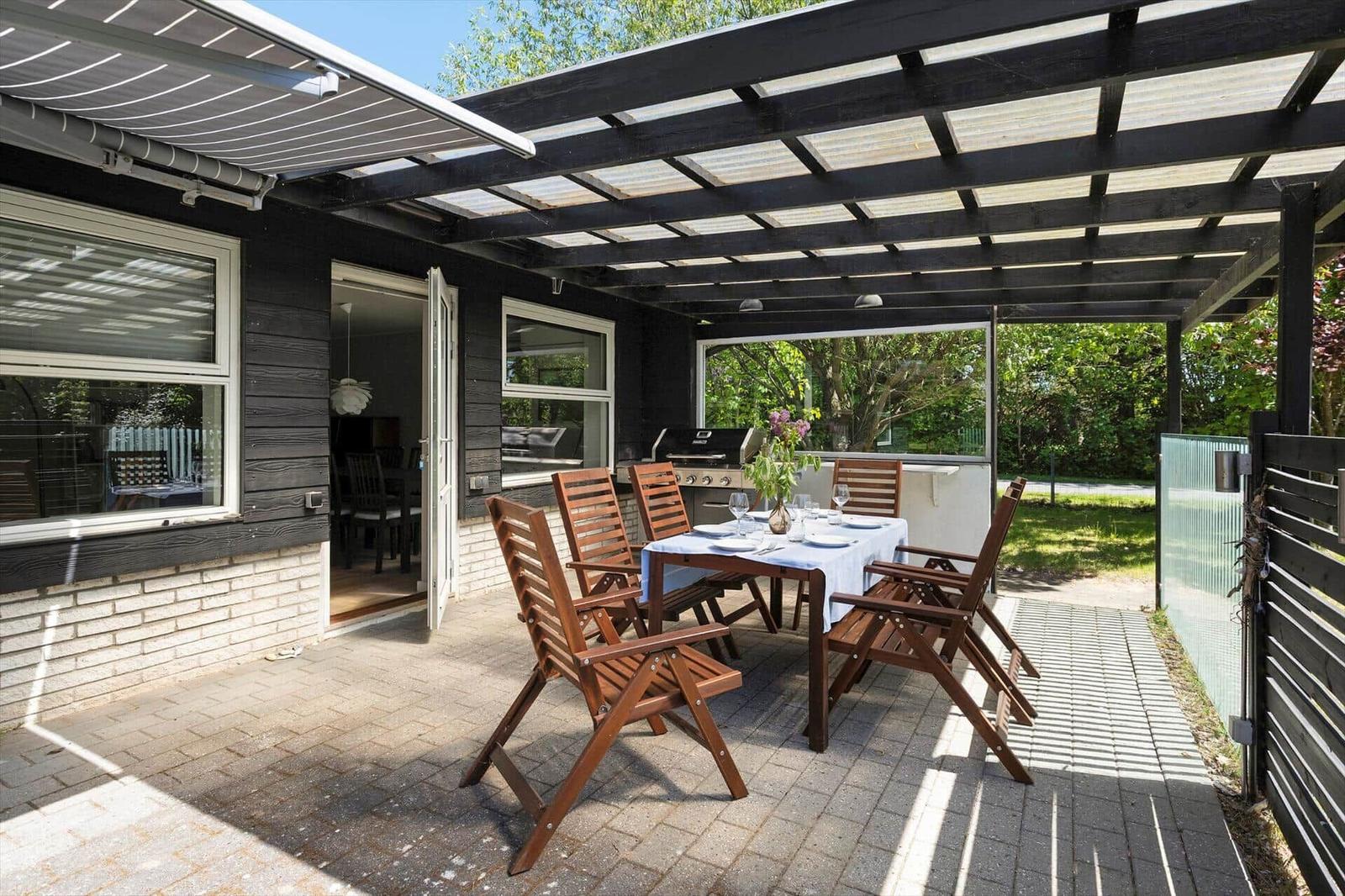 Terrace with table, chairs, and grill under roof