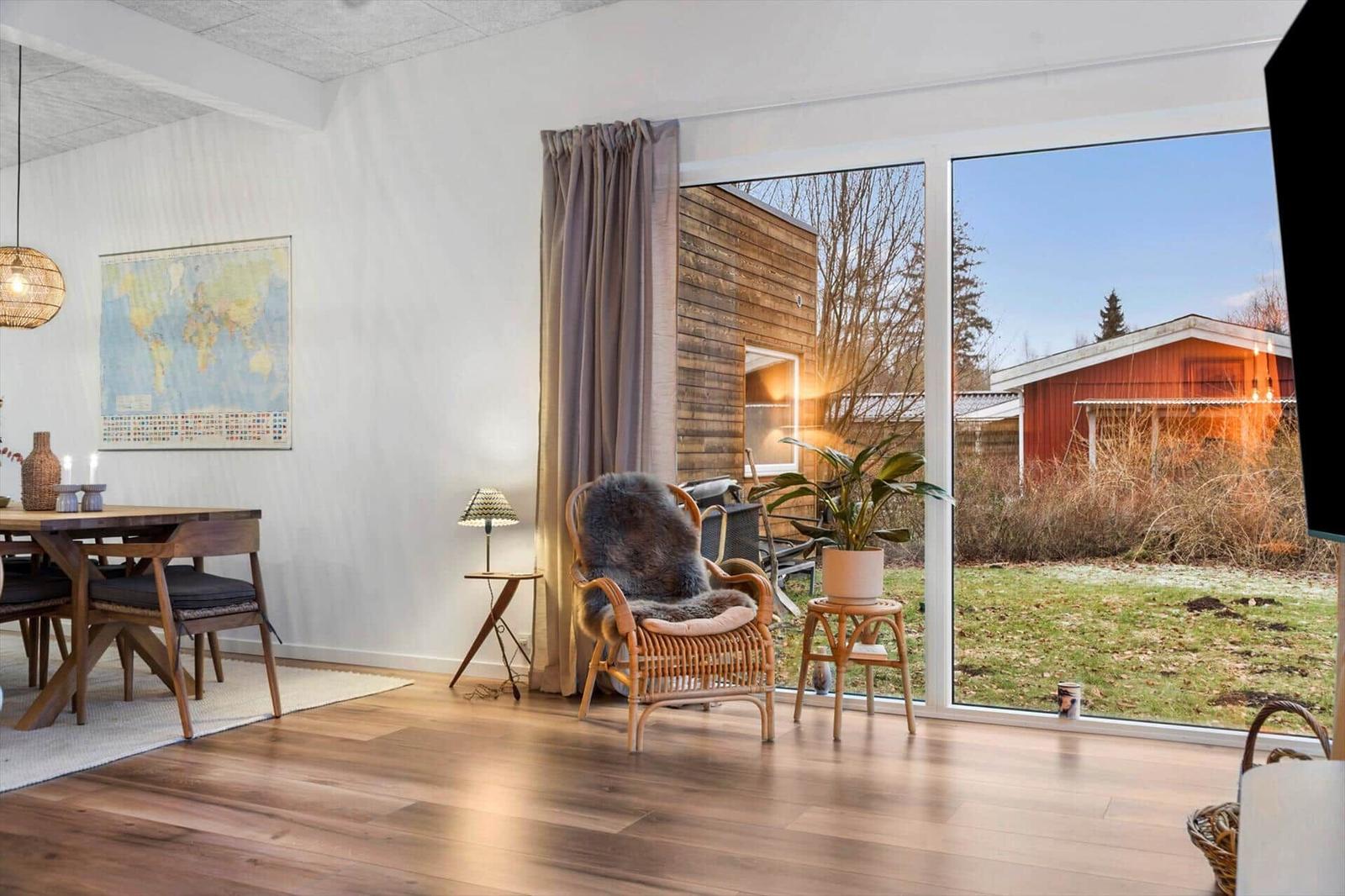 Dining area with wooden table, chairs, and world map. Kitchen in background.