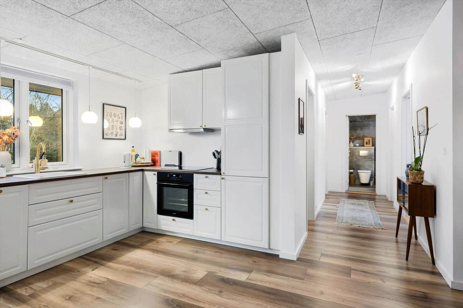 Entryway with mirror cabinet, coffee machine, and wooden floor.