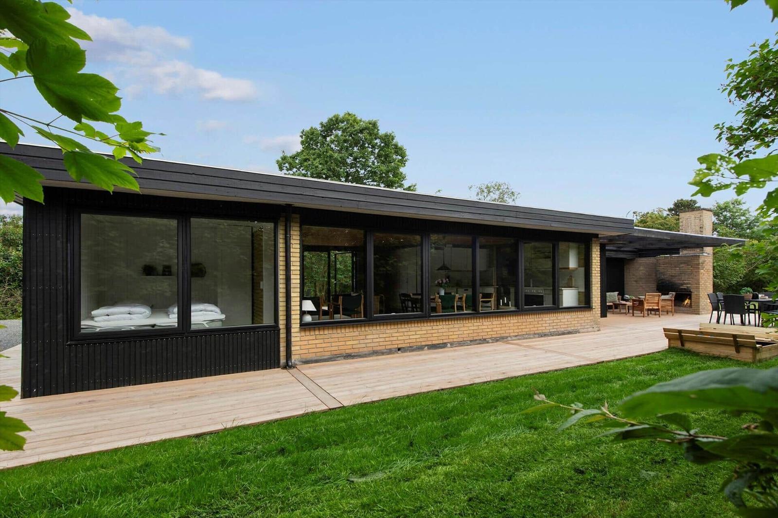 Modern villa with large wooden deck and garden. View inside with sleeping and dining areas.