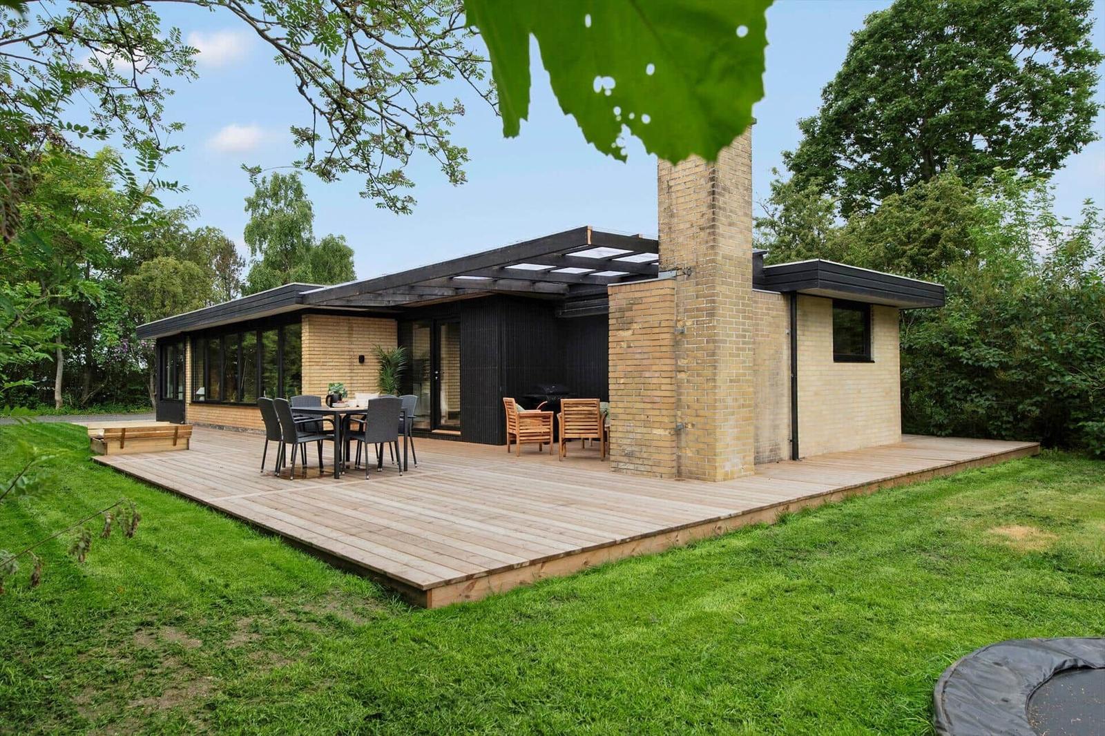 Modern villa with terrace, grill area, and garden. Wooden terrace with seating.