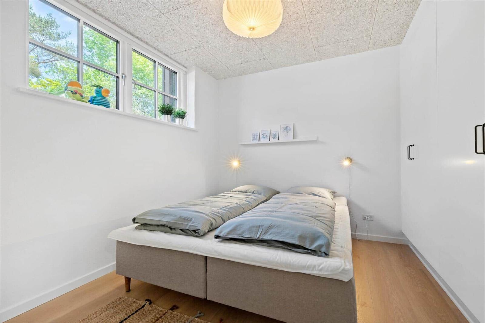 Bedroom with double bed, large window, and wooden floor.