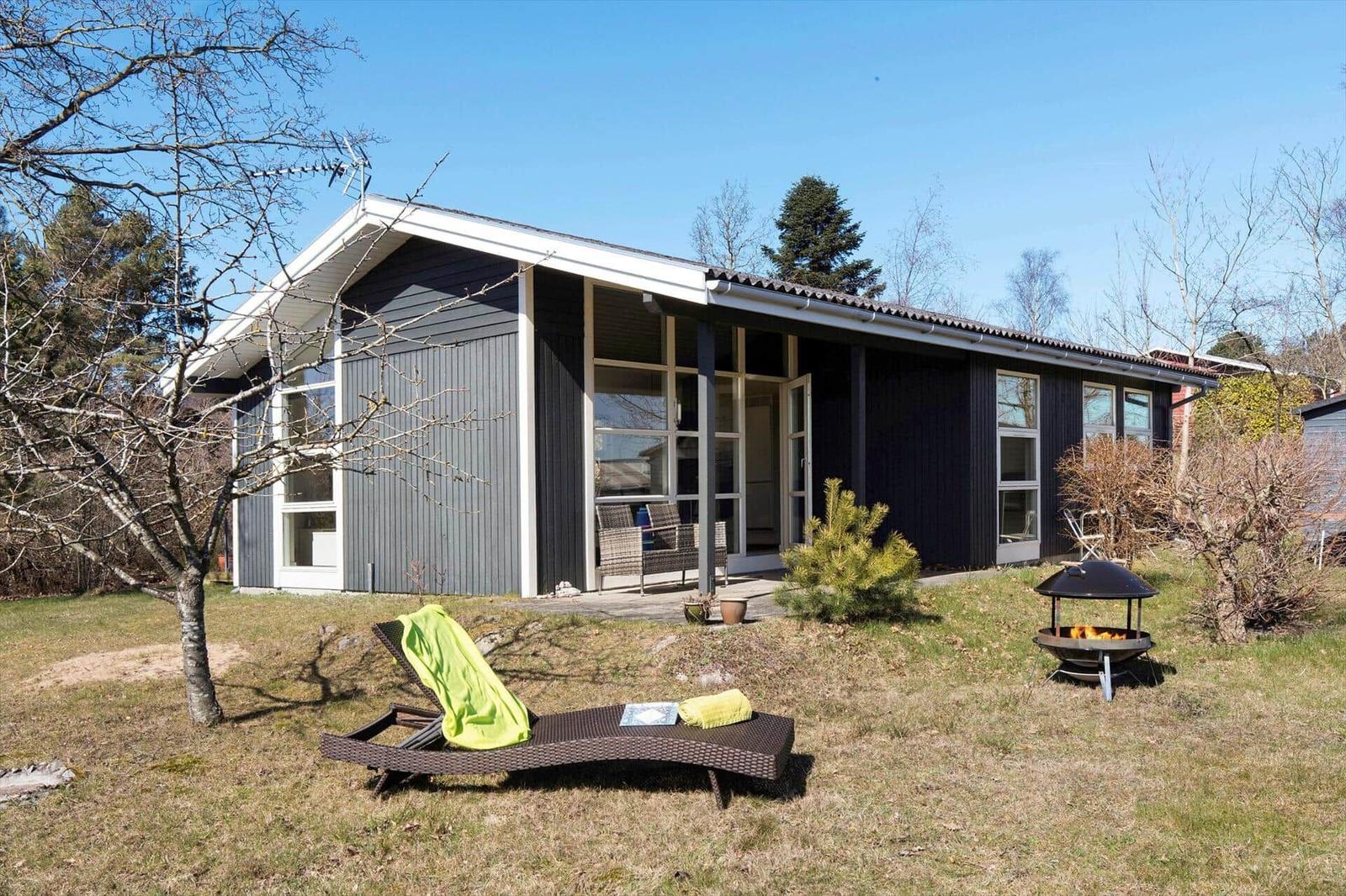 Moderne Villa mit Terrasse, Liegestuhl und Grill im Garten.