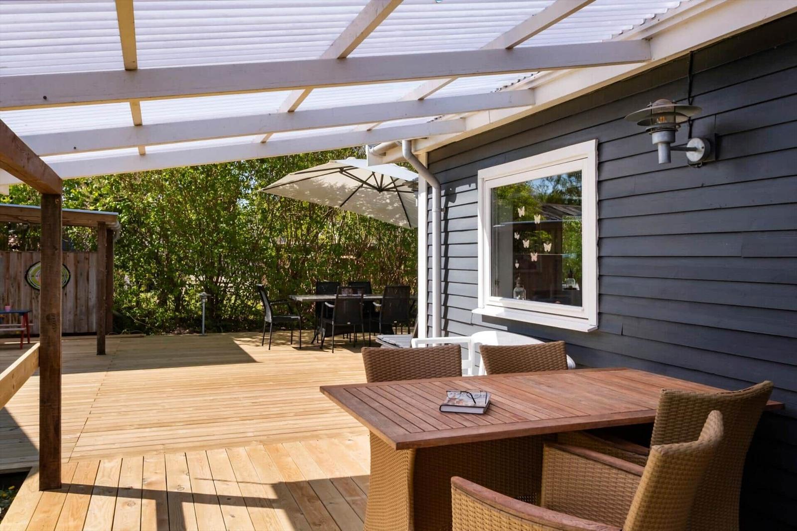 Deck with table, chairs, and shade under roof