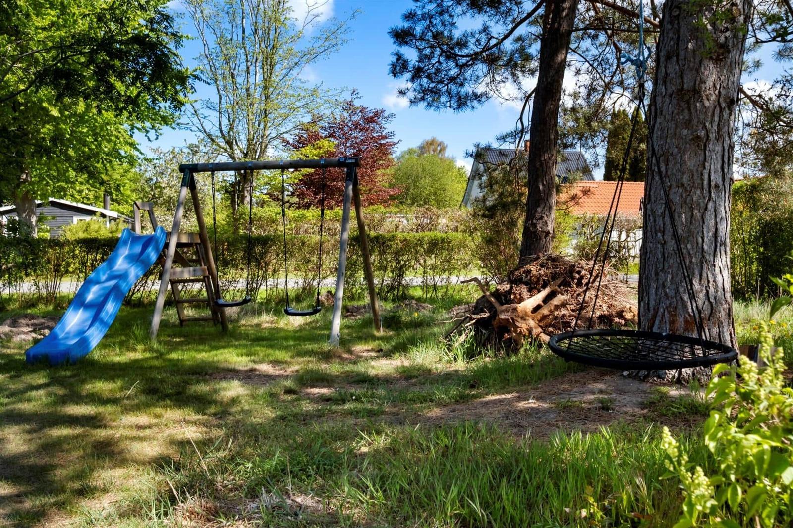 Backyard with playground, slide, and swing under trees.
