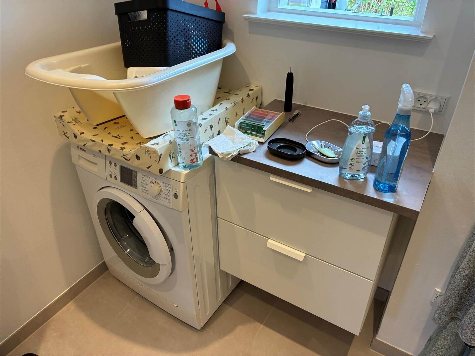 Washing machine with basin and worktop with cleaning supplies