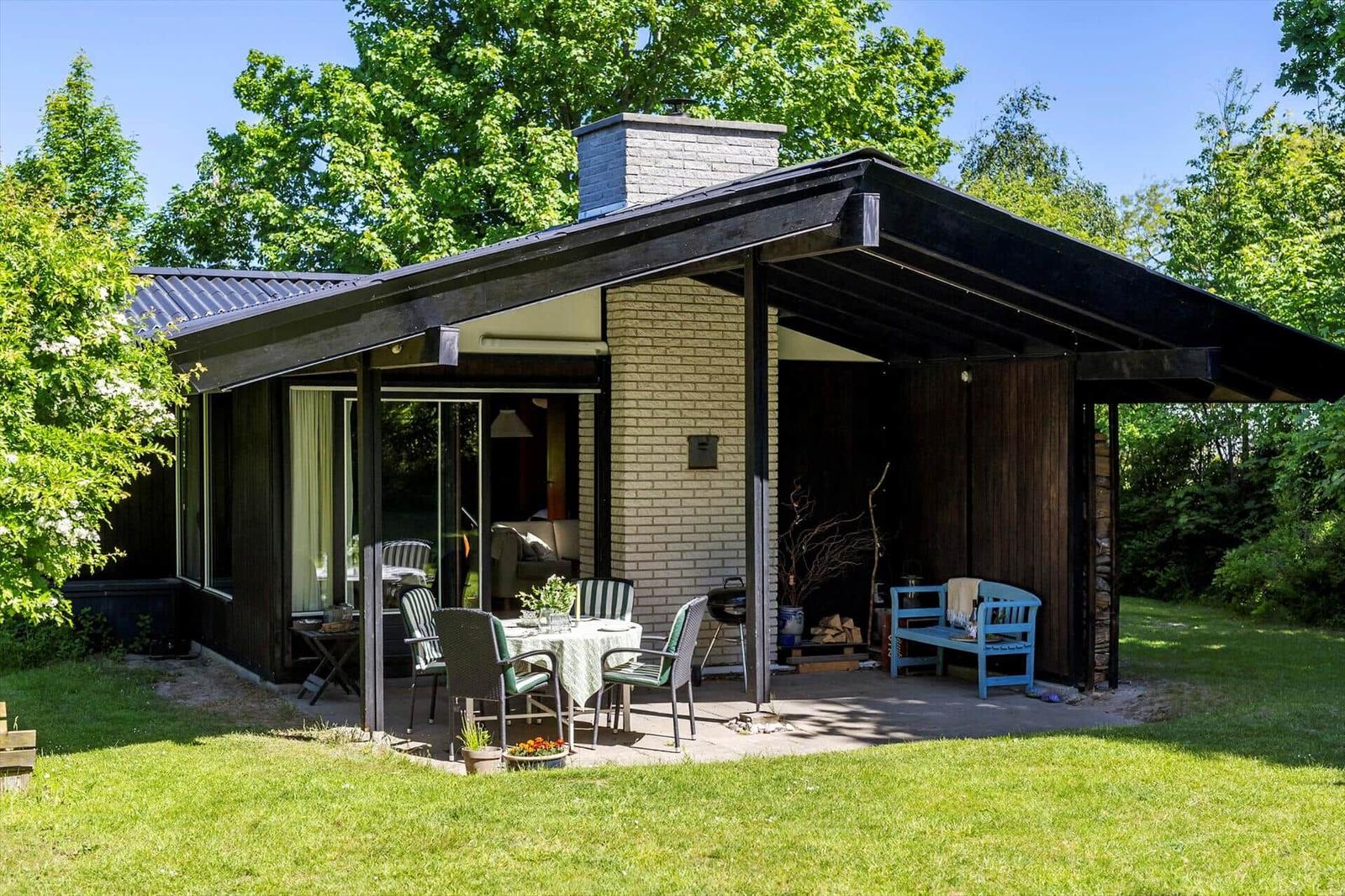House with terrace, garden, and grill area. Blue bench and table with chairs.