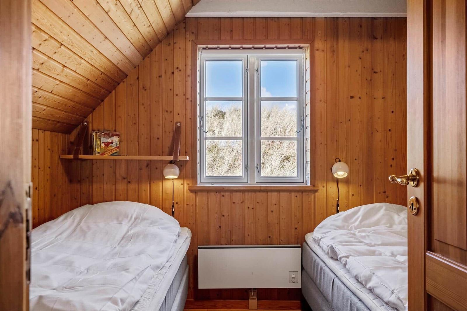 Two beds in a wood-paneled room with skylight and wall heater.