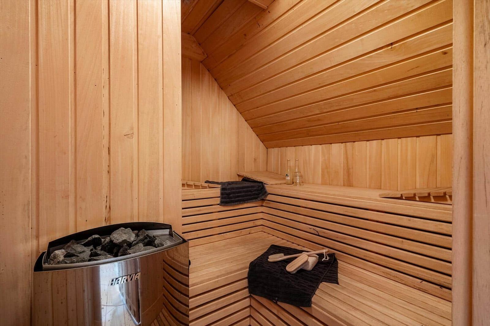 Sauna with wooden bench, stones, and towel