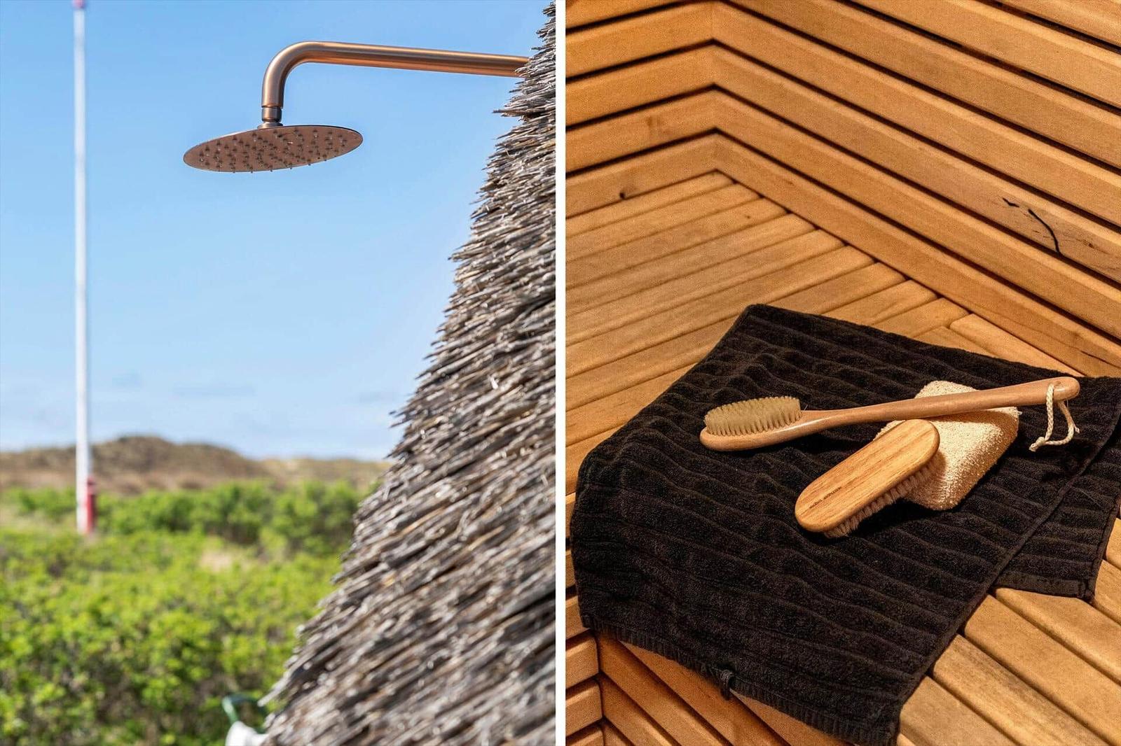 Outdoor shower with thatched roof and sauna with wooden bench and towels.