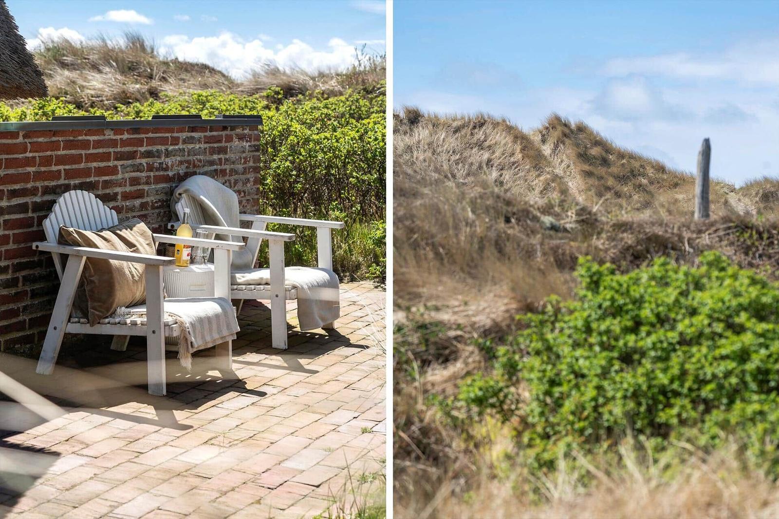 Terrace with two white chairs and view of dunes.