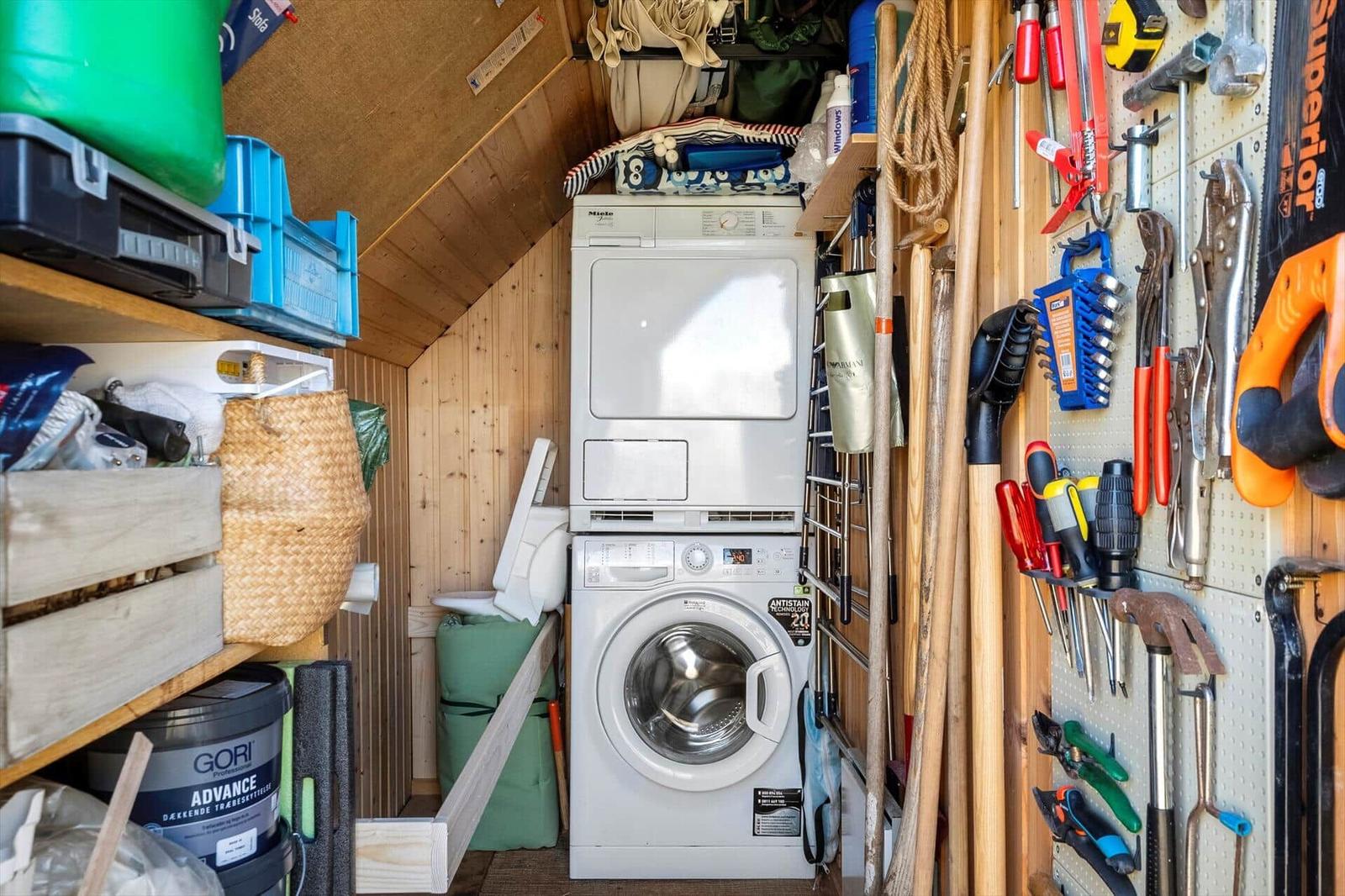 Washing machine and dryer in a tool room with shelves and tool wall.