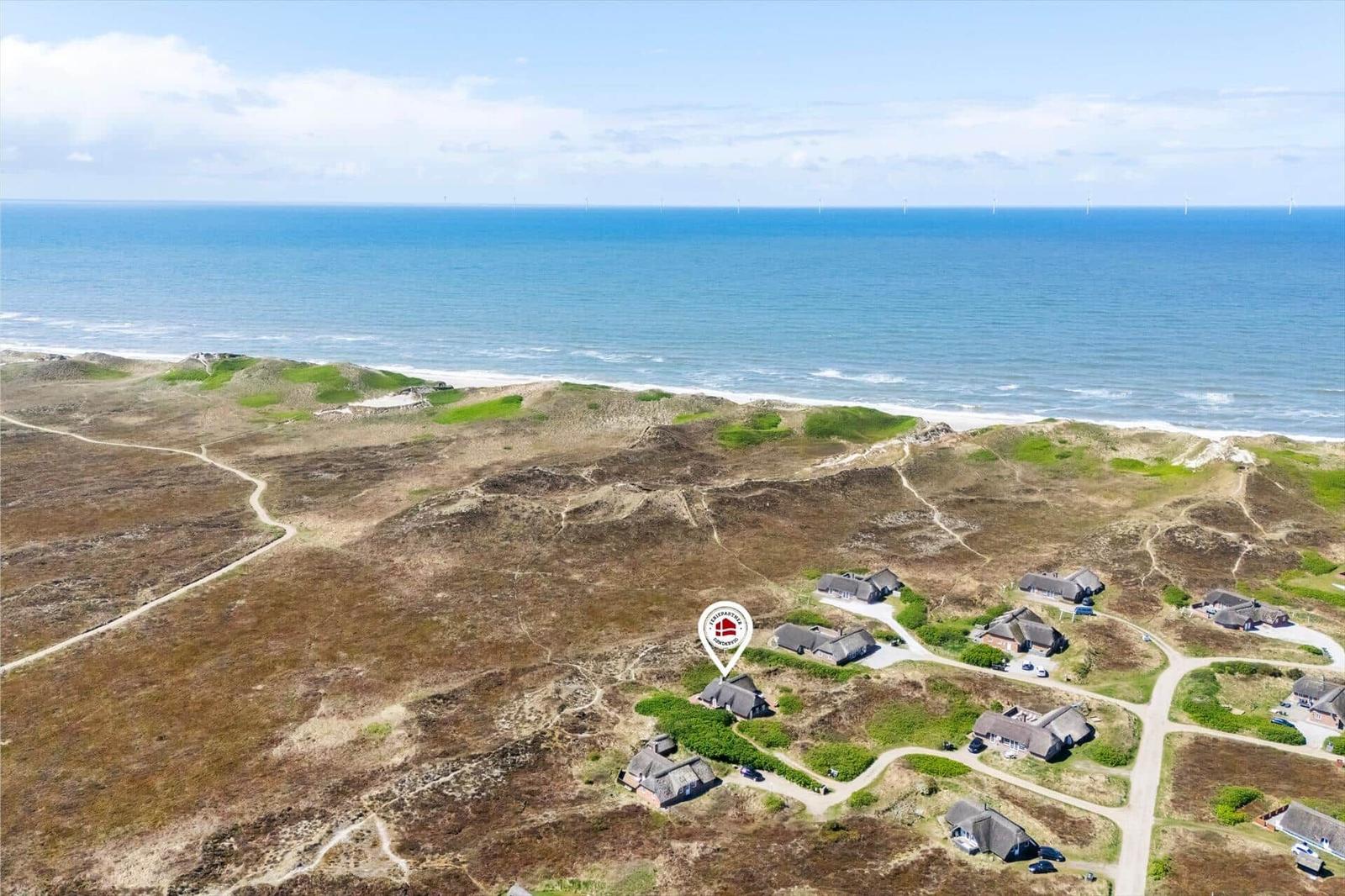 House near beach with view of North Sea and wind turbines