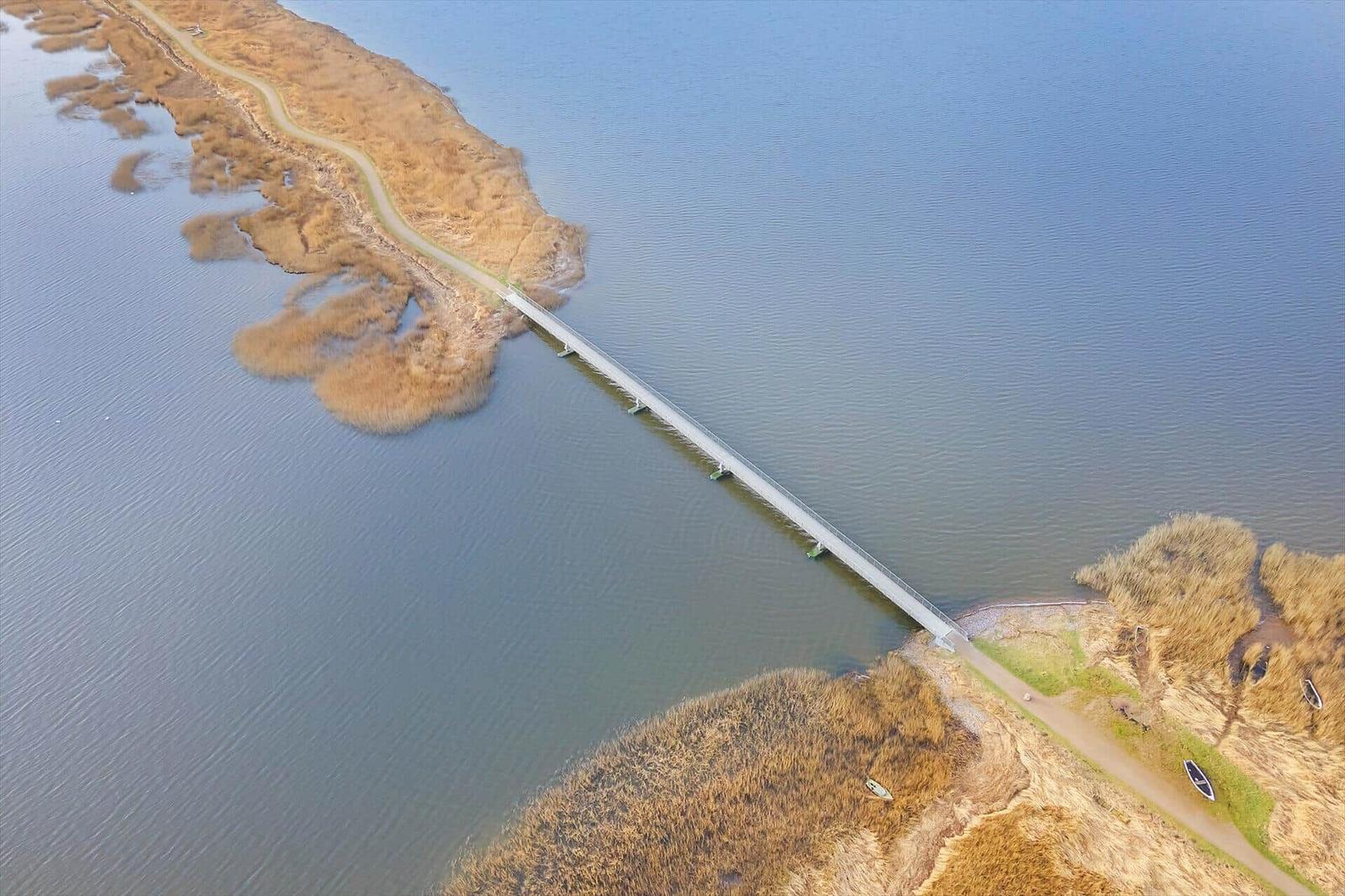 Bridge spans water between two shorelines with vegetation.