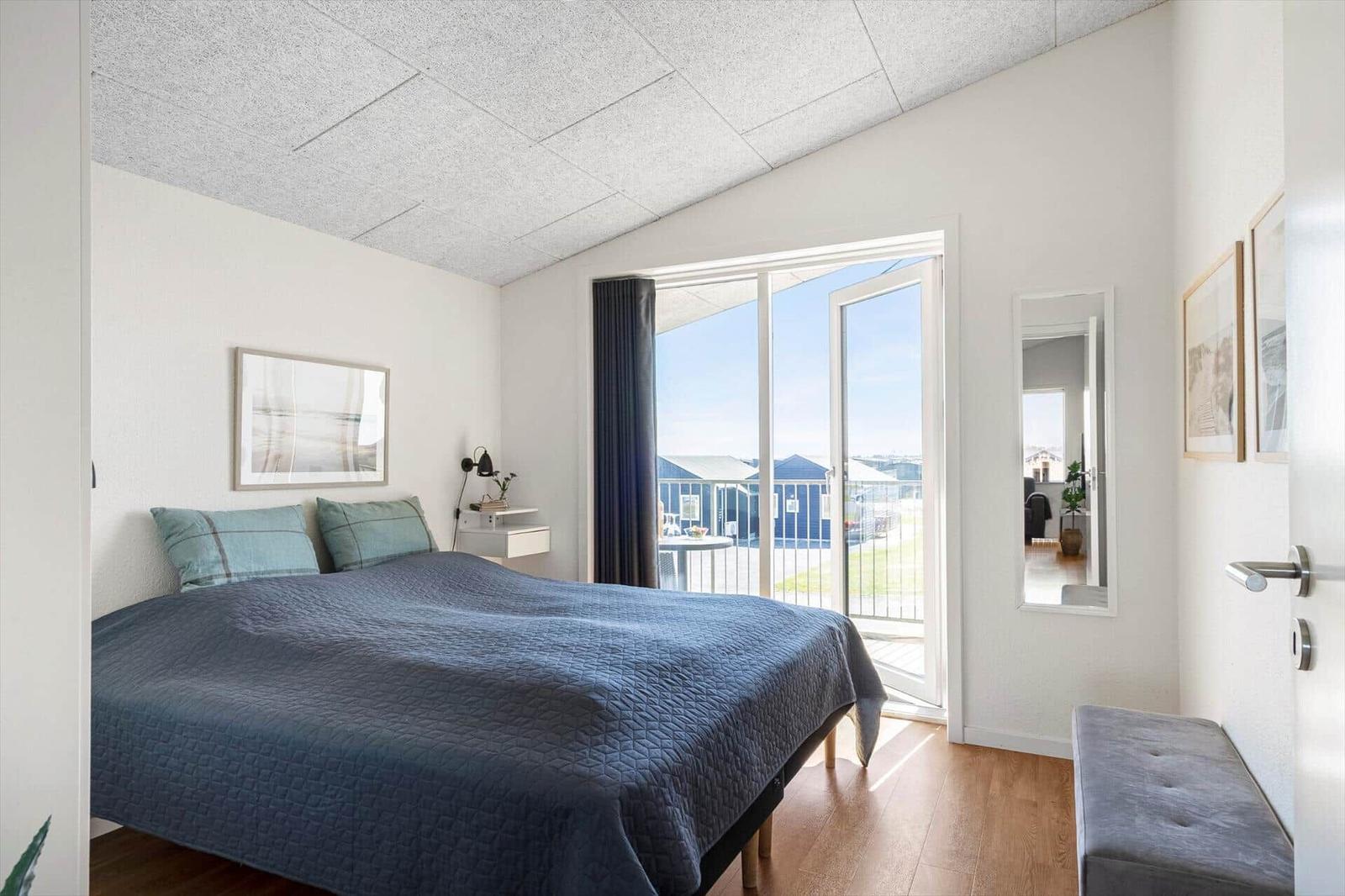 Schlafzimmer mit Bett, Balkon und Spiegel an der Wand.