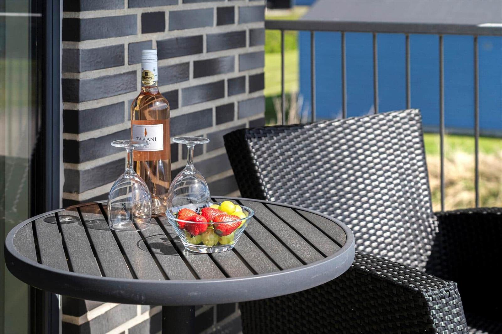 Rundtisch mit Weinflasche, Gläsern und Obst auf Balkon
