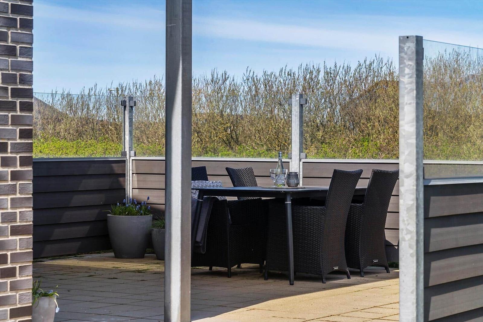 Terrasse mit Tisch und Stühlen, Glasgeländer und Pflanzen