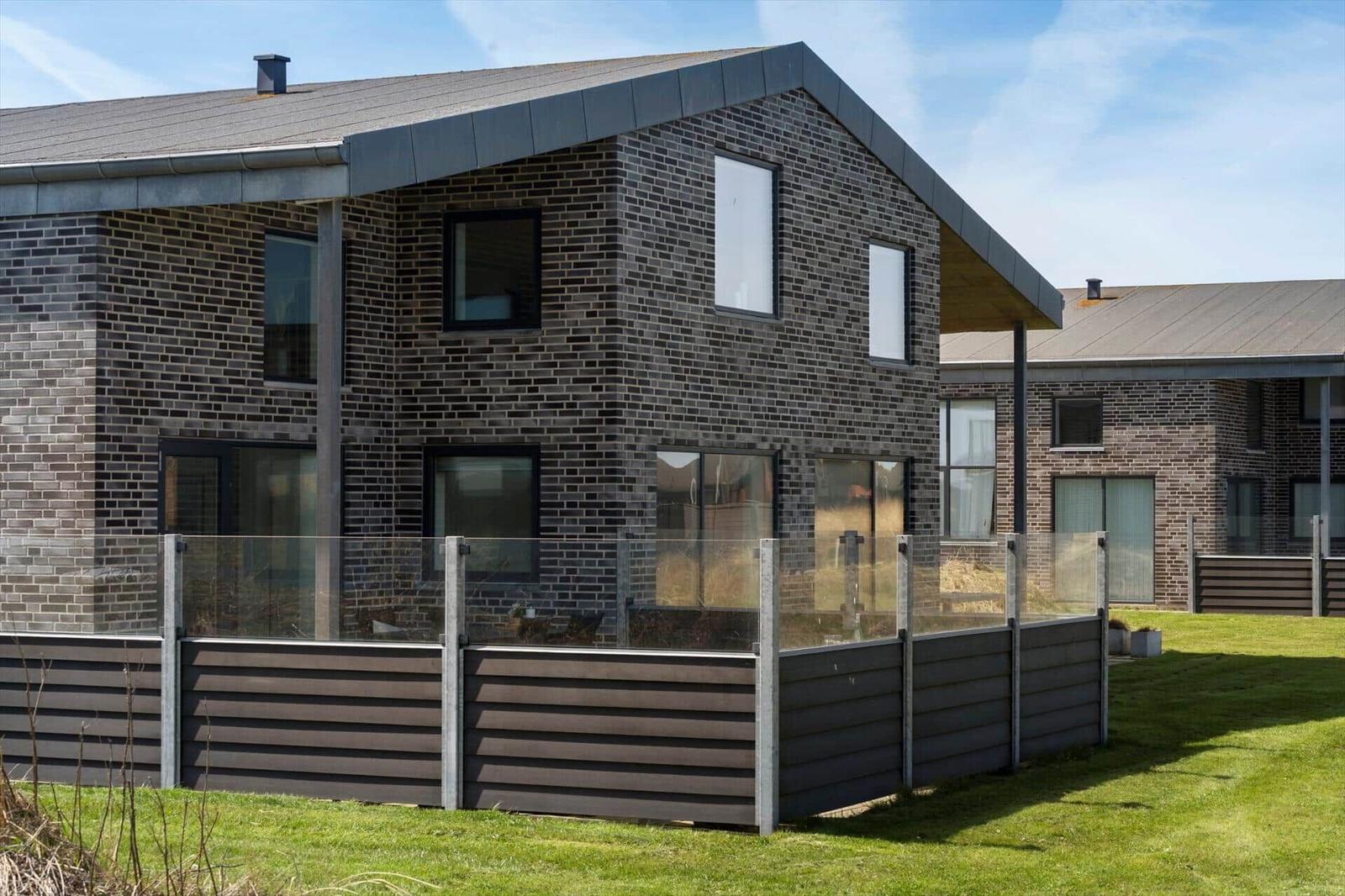 Moderne zweistöckige Villa mit dunklem Ziegelmauerwerk und großzügigen Fenstern.