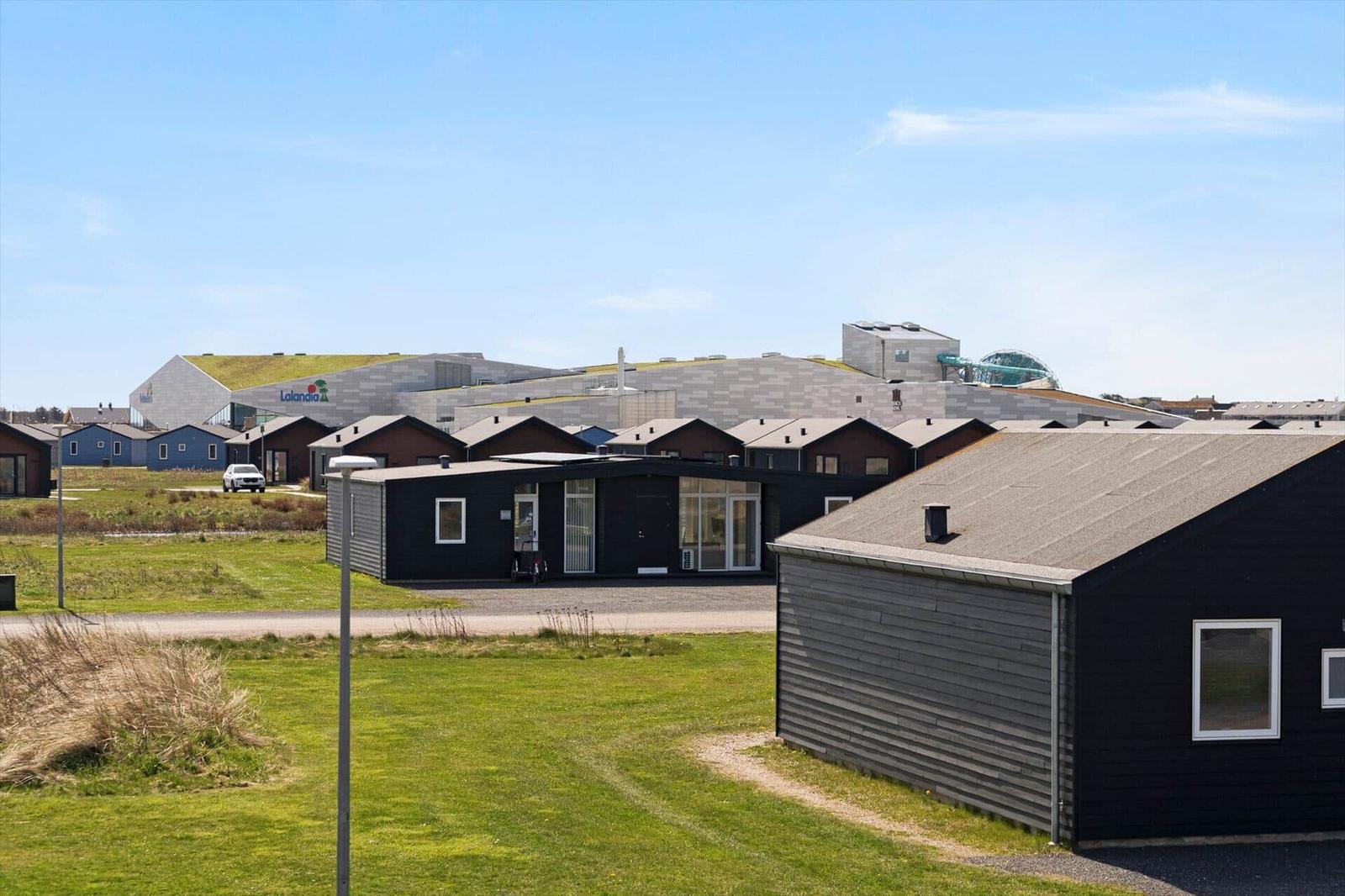 Moderne Holzhausbauweise mit grünem Dach und großzügigen Fenstern in einer ländlichen Umgebung.