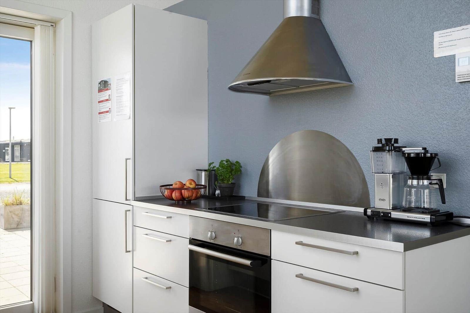 Moderne Küche mit Edelstahlherd, Kühlschrank und Kaffeemaschine.
