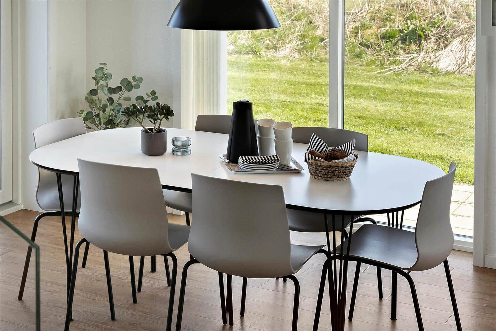 Rundes Esszimmer mit Tisch, Stühlen und Blick auf Garten.
