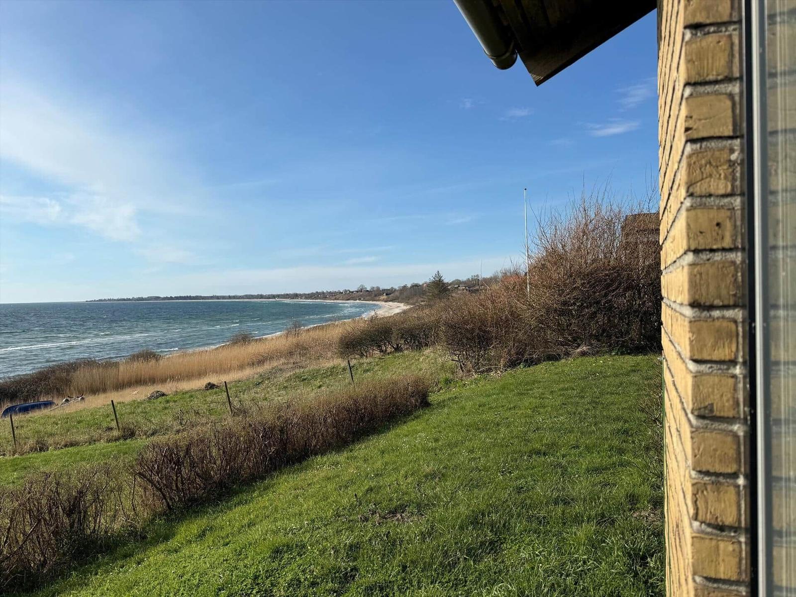 Von der Terrasse bietet sich ein Blick auf das Meer und eine grüne Wiese.
