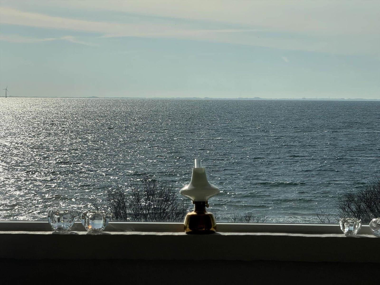 Blick auf das Meer mit Windrad, Kerzenhalter und Laterne auf Fensterbank