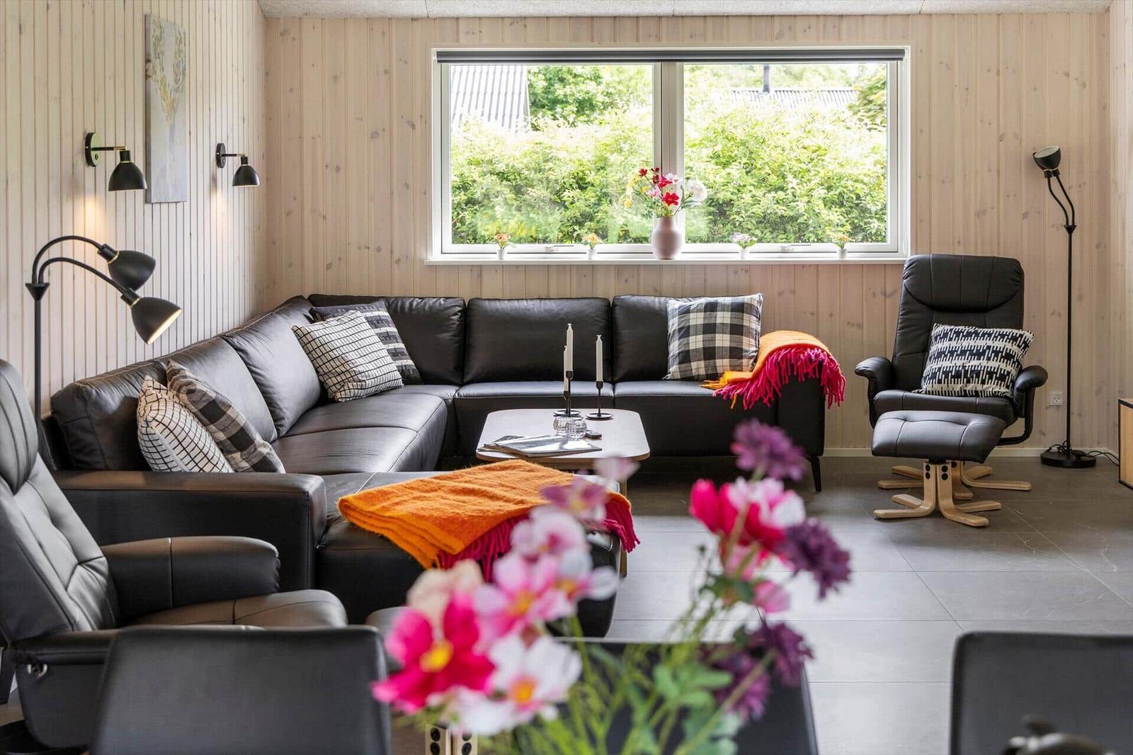 Living room with leather sofa, chair, and view of greenery