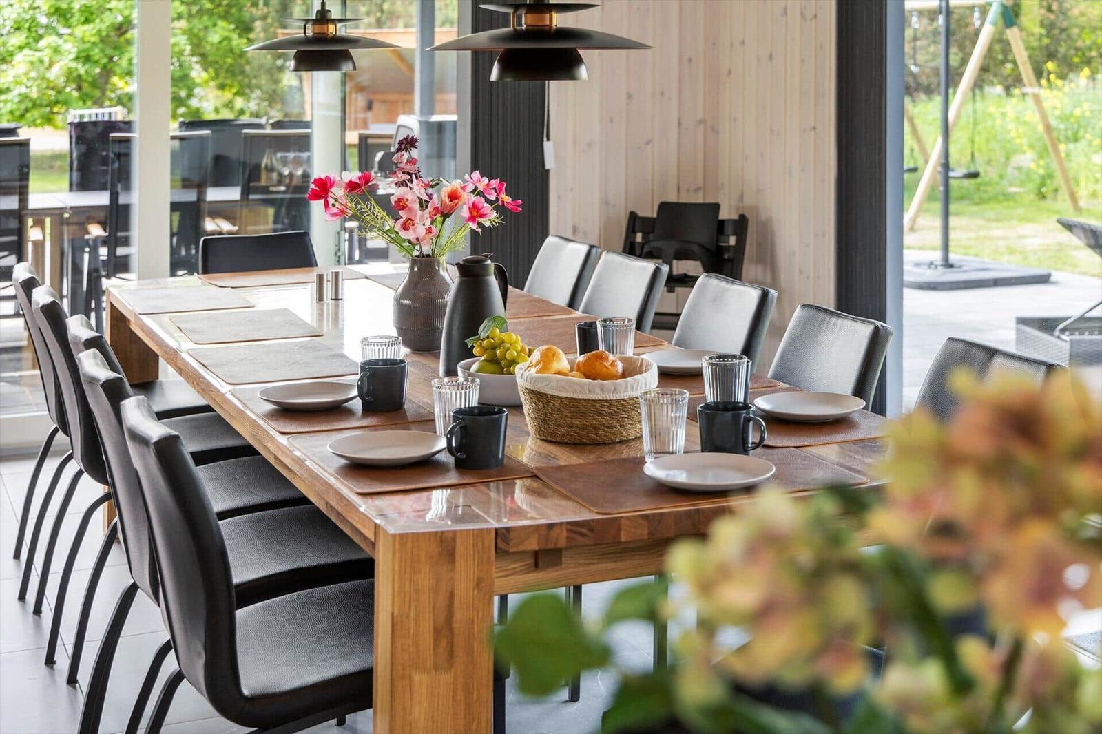 Long wooden table with chairs, flowers, and fruit in dining room.