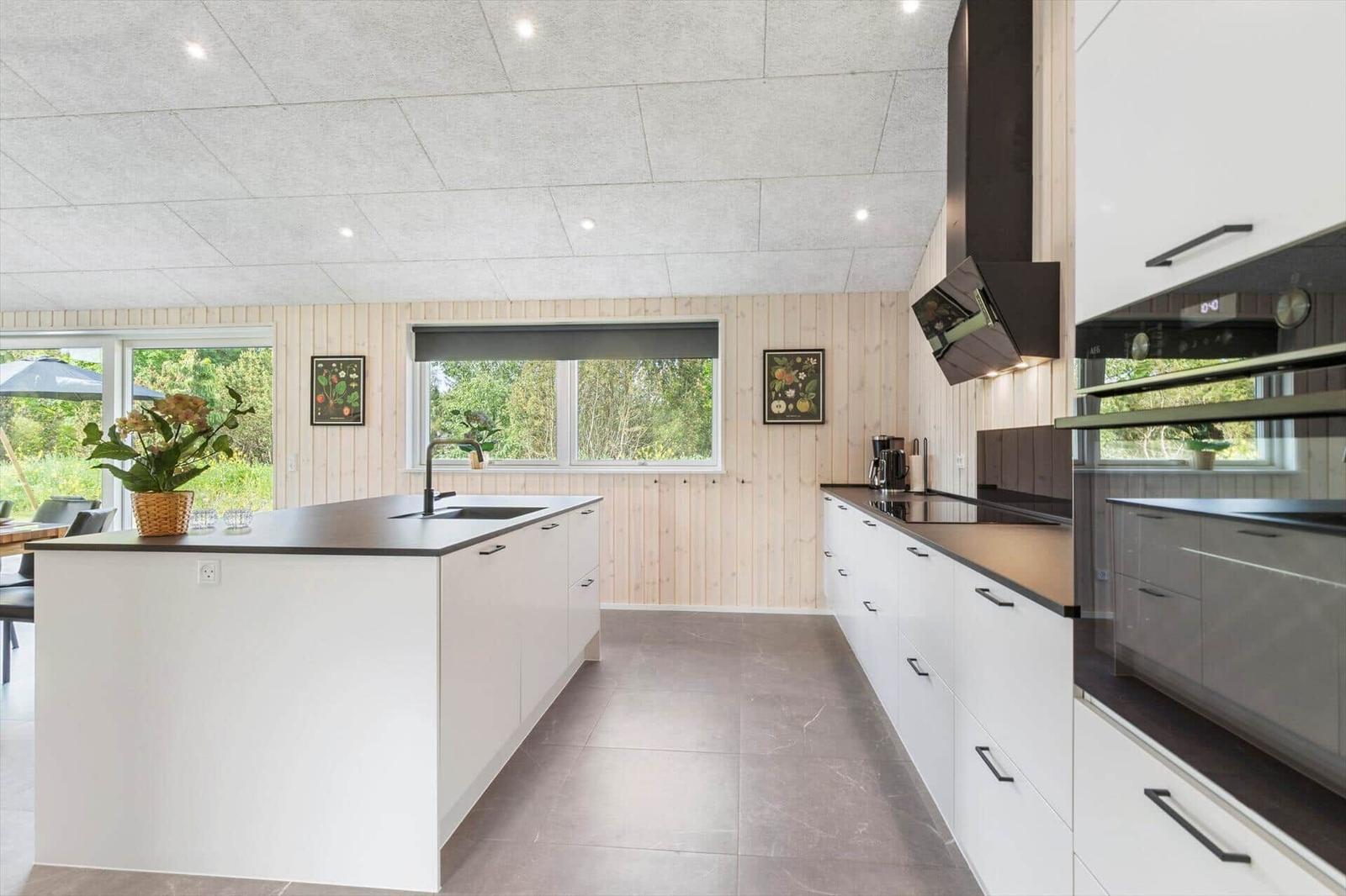 Modern kitchen with island, white cabinets, and dark worktops.