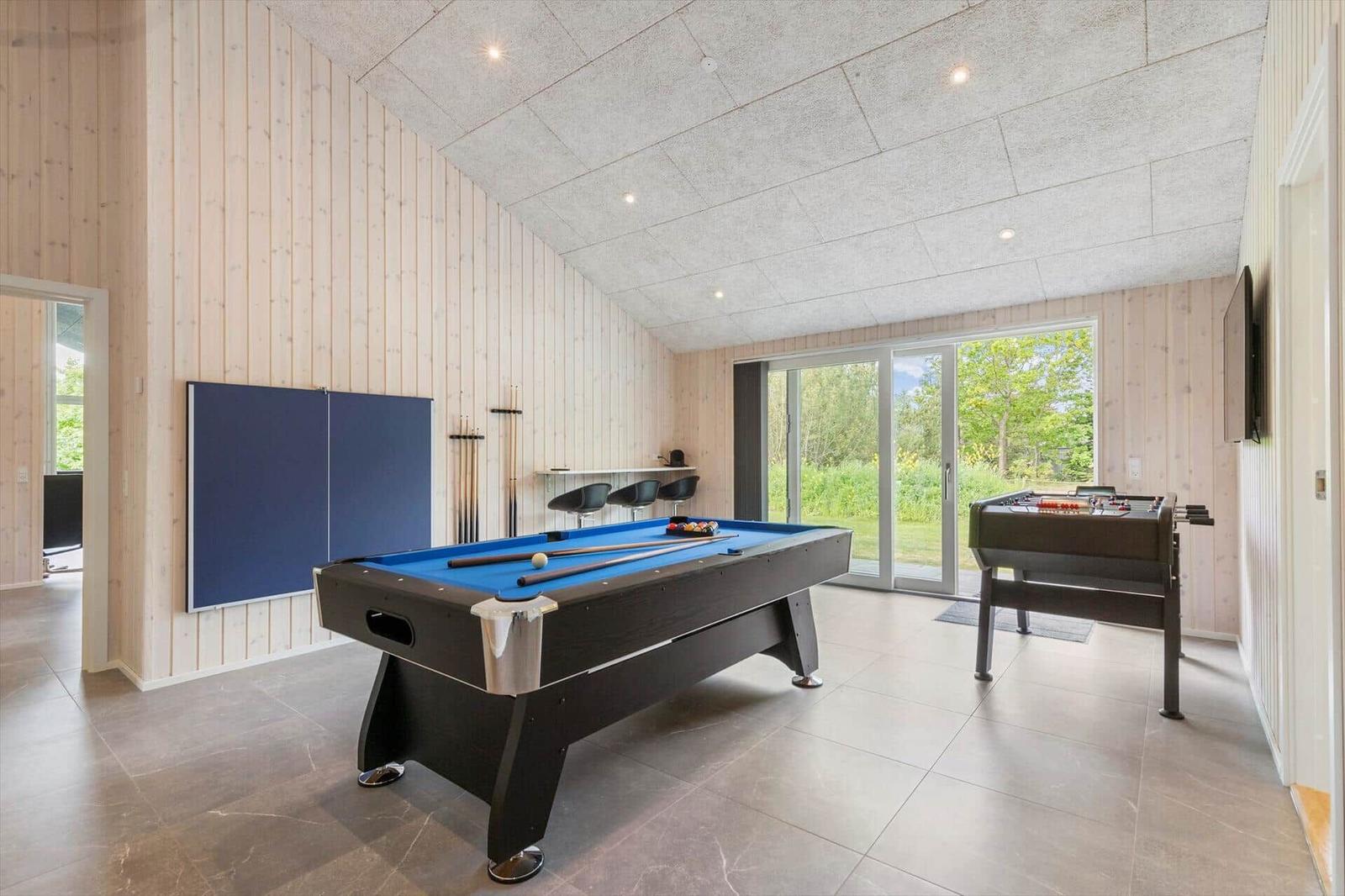 Room with pool table, foosball table, and window to outdoor terrace.