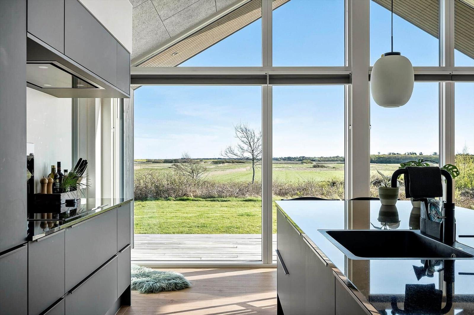 Moderne Küche mit großem Fensterblick auf grünes Feld und Himmel