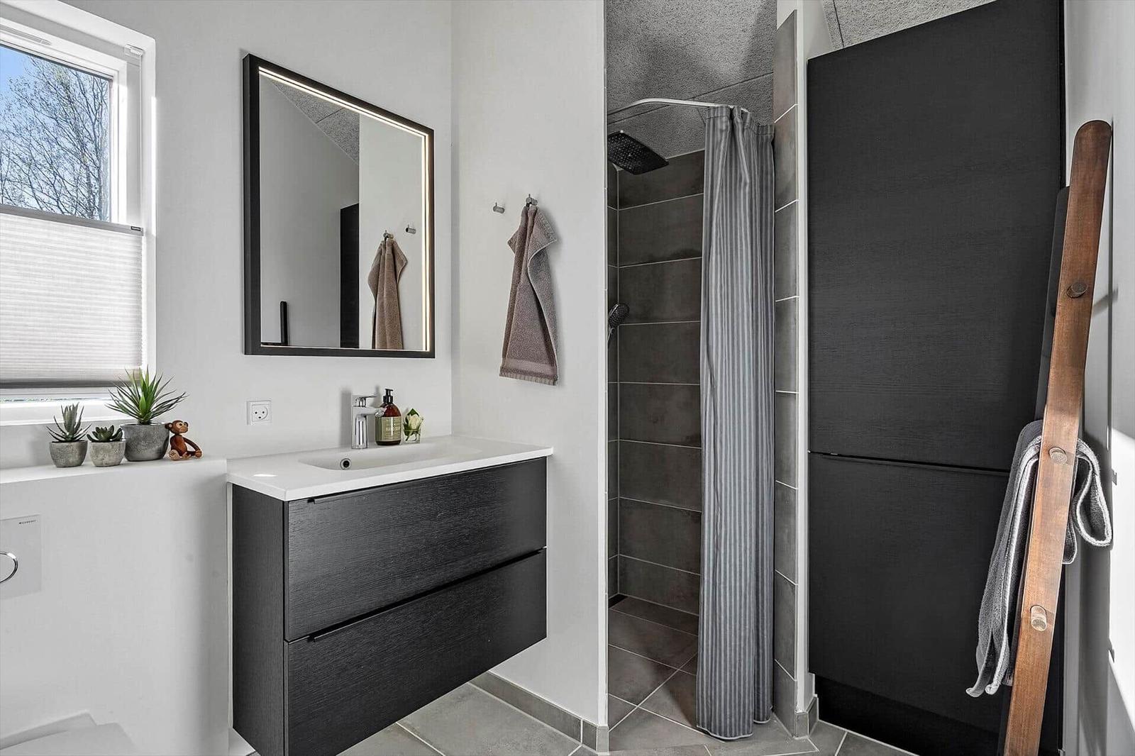 Badezimmer mit Dusche, Waschbecken und Fenster
