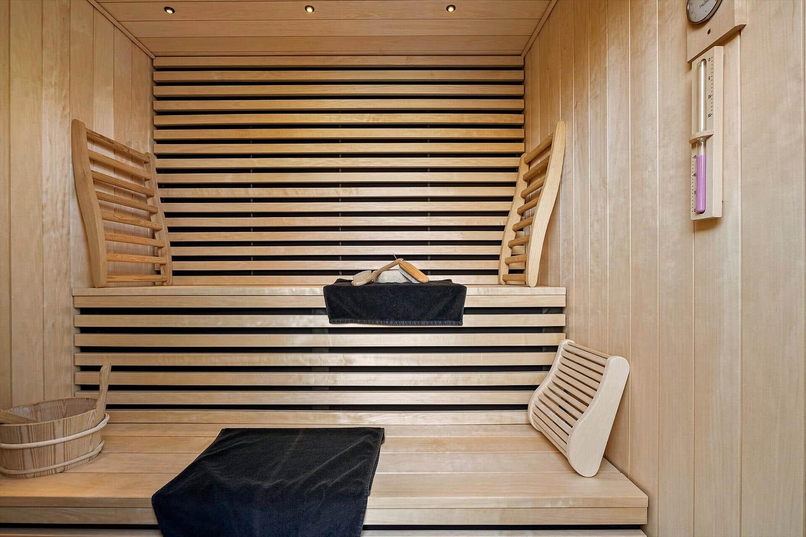 Sauna mit Holzbank, Handtuch und Thermometer an der Wand.