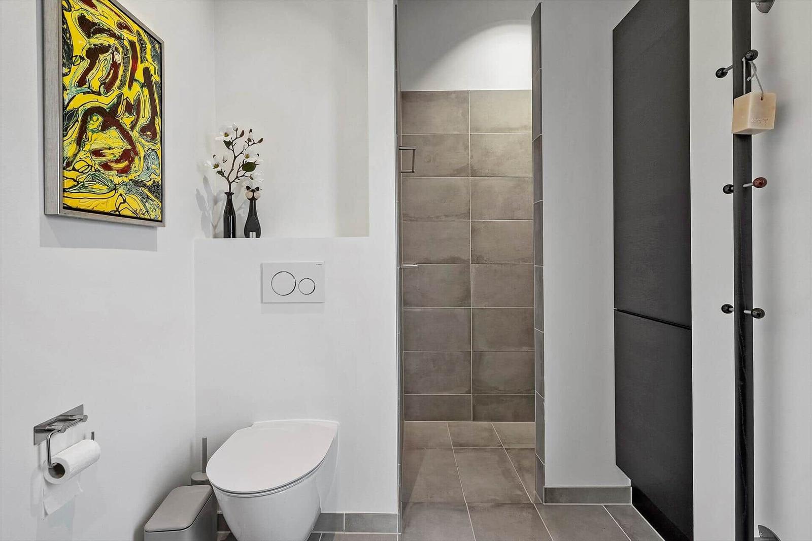 Badezimmer mit Toilette, Dusche und Wandbild.