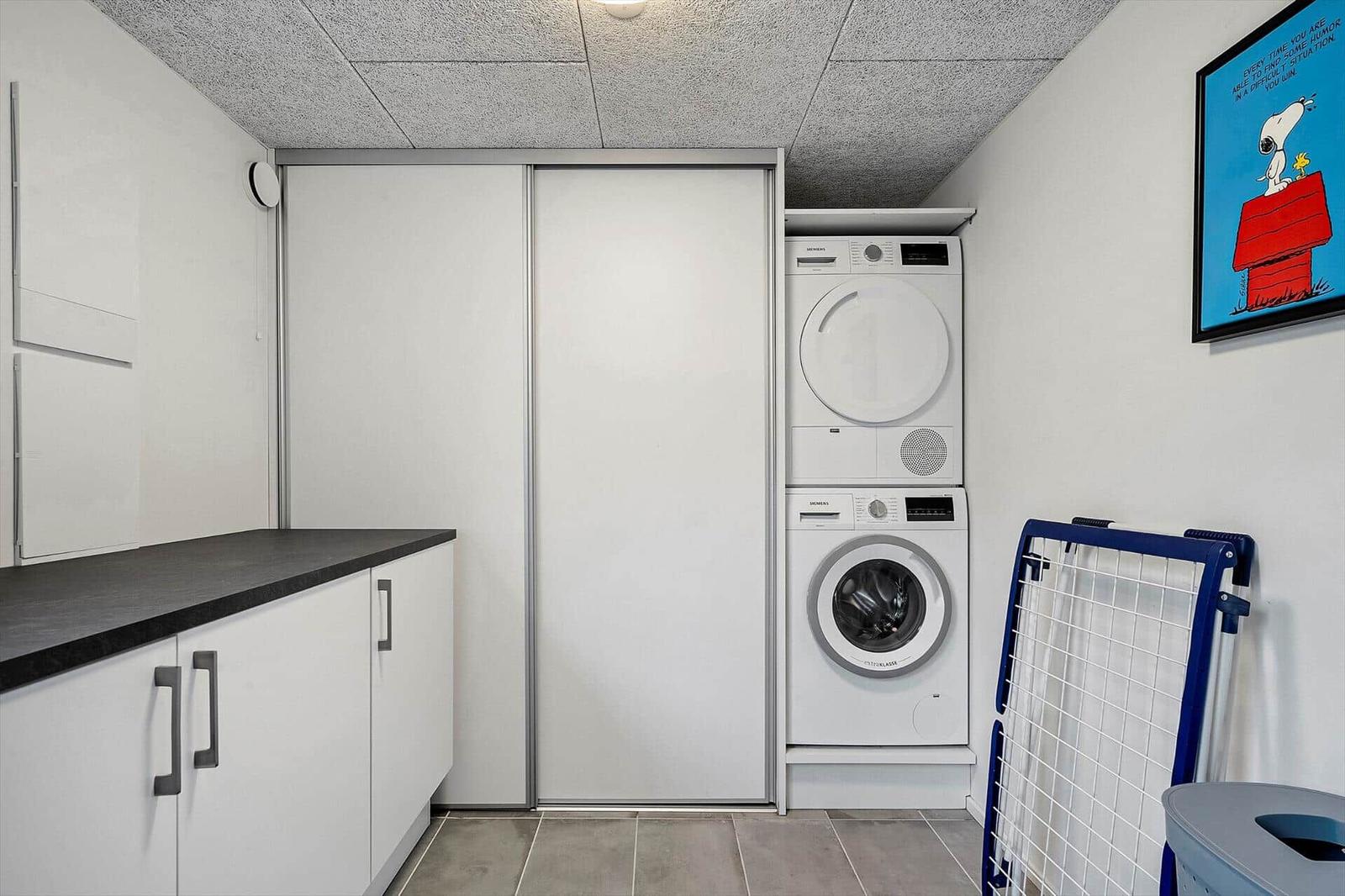 Wäscherei mit Waschmaschine und Trockner, Schrank und Wäscheständer.