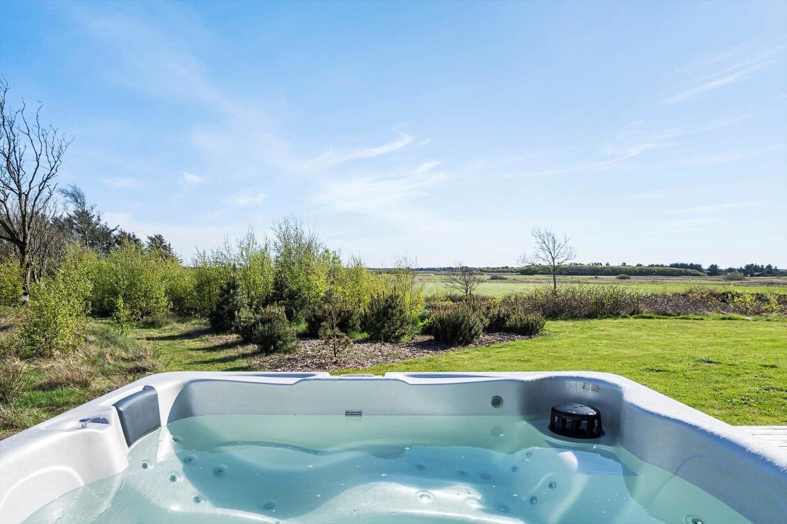 Ein Whirlpool mit Blick auf einen grünen Garten und Wald.