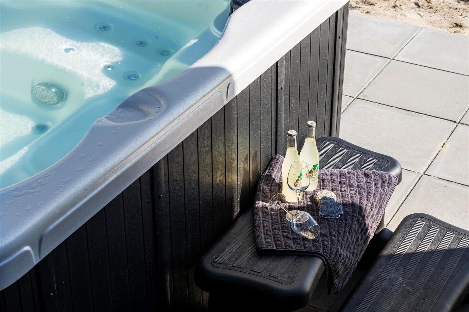 Hochwertige Whirlpool-Oase mit Getränken und Handtuch auf Terrasse.