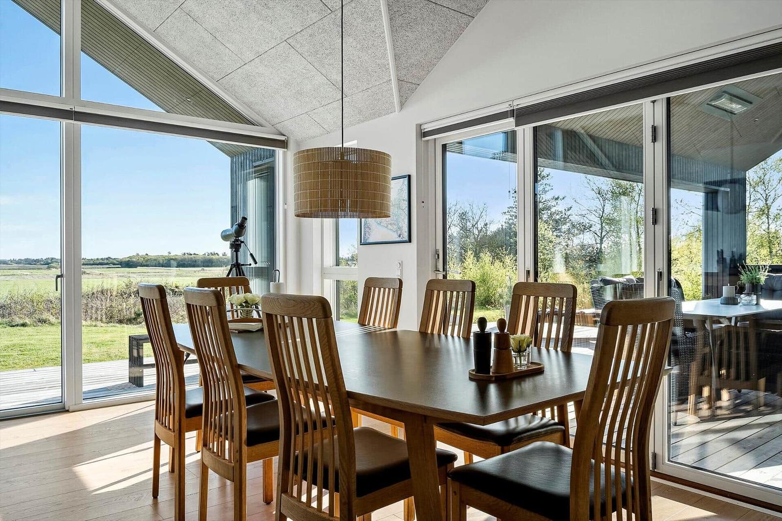 Essbereich mit Holztisch und Stühlen, großzügige Fenster mit Blick auf die Landschaft.