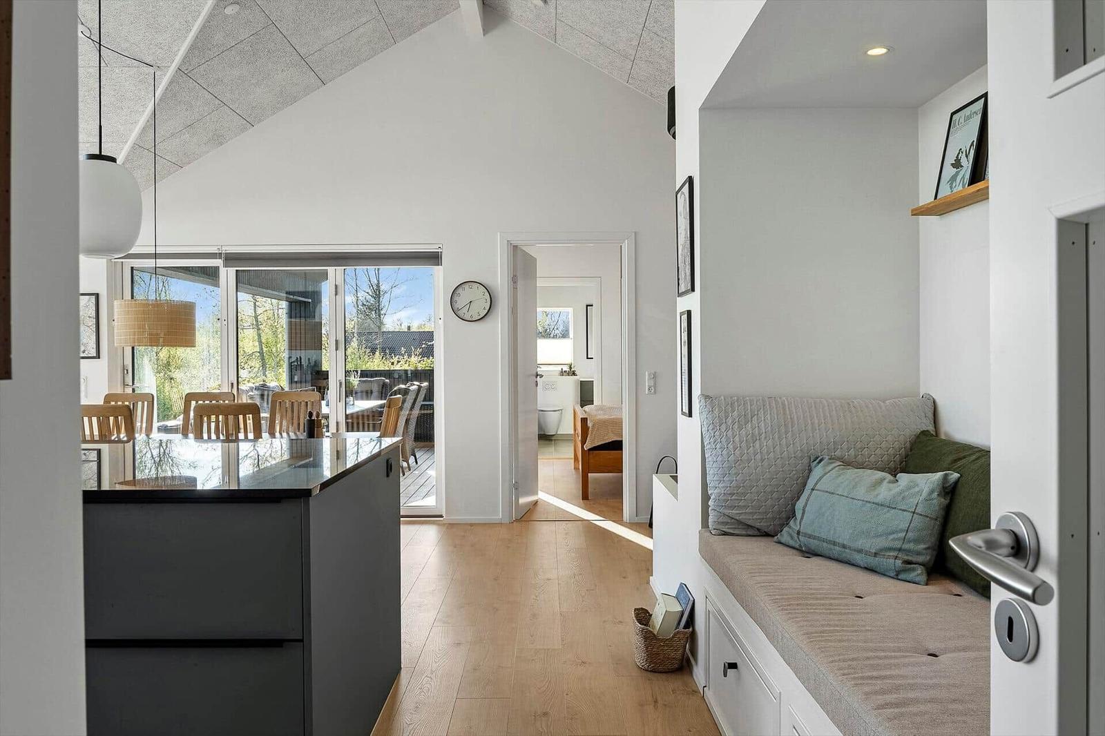 Haus mit Essbereich, Schlafzimmer und Sitzbank. Holzboden und große Fenster.