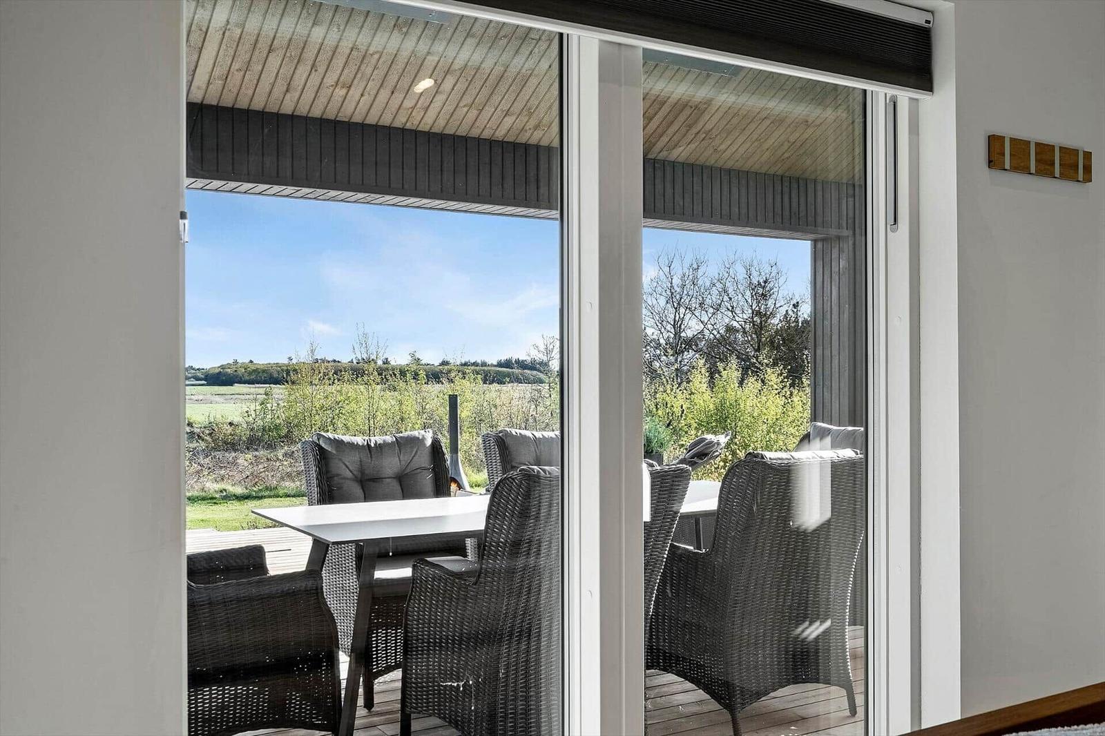Terrasse mit Tisch und Stühlen, Blick auf Feld und Bäume.
