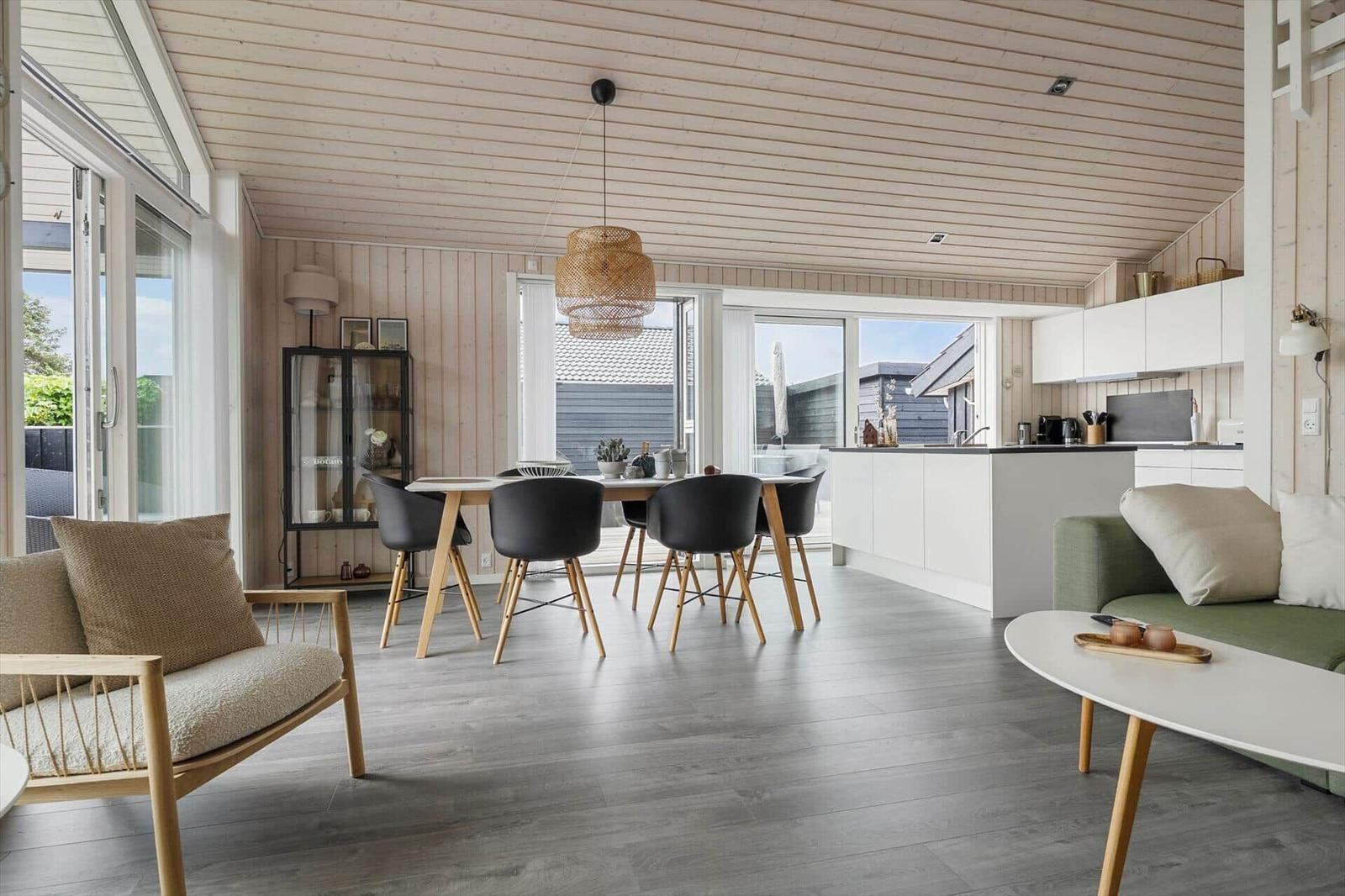 Wohnbereich mit Essbereich und Küche. Holzdecke, große Fenster und moderne Möbel.