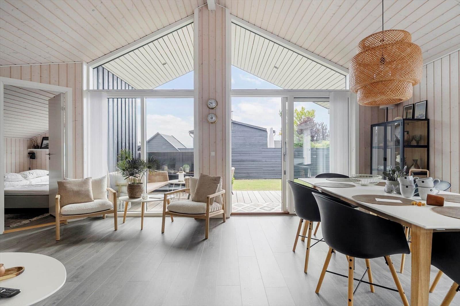 Wohn- und Essbereich mit Blick auf die Terrasse. Holzdecke, Sitzgelegenheiten und Essplatz.