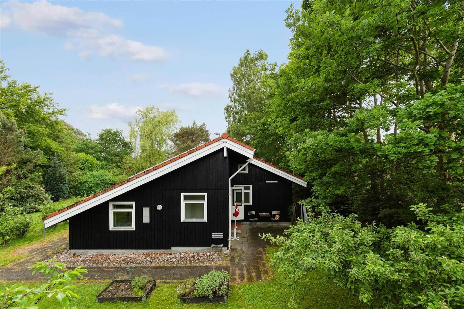 Black wooden house with white trim and terrace in the green