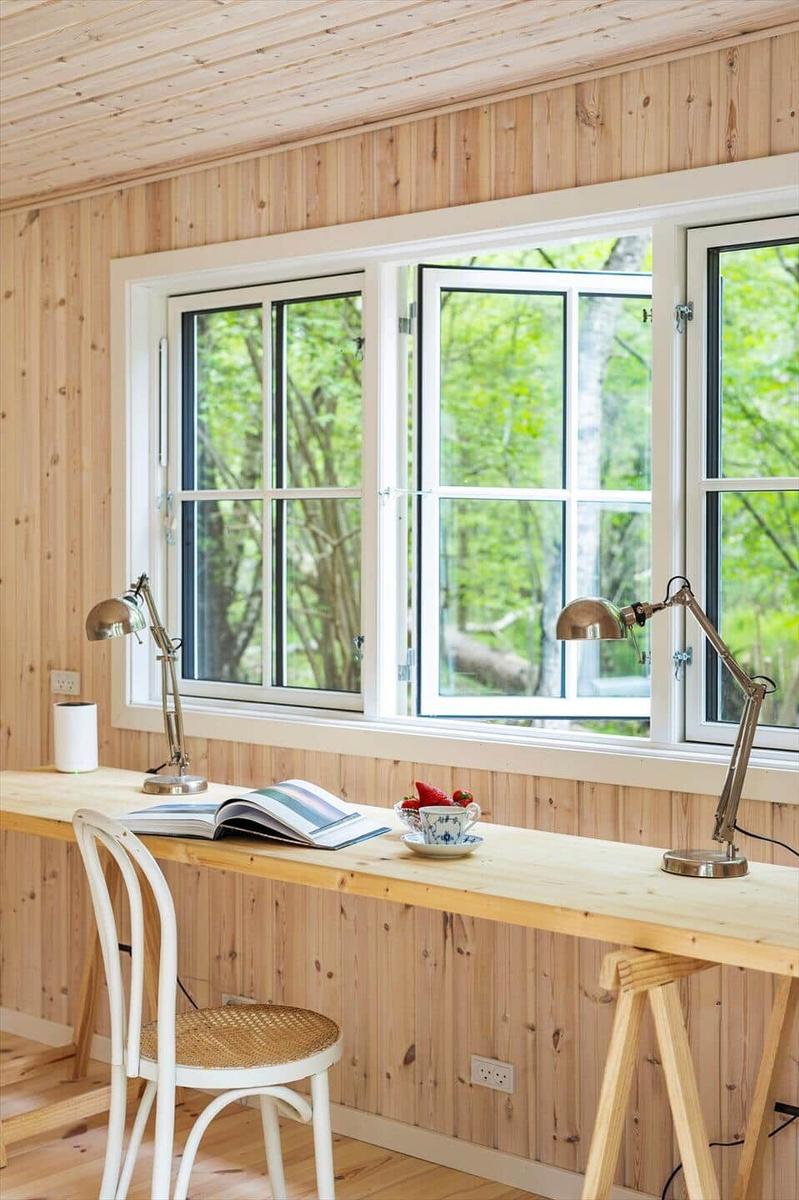 Schreibtisch mit Stuhl, Lampe und Blick auf Wald