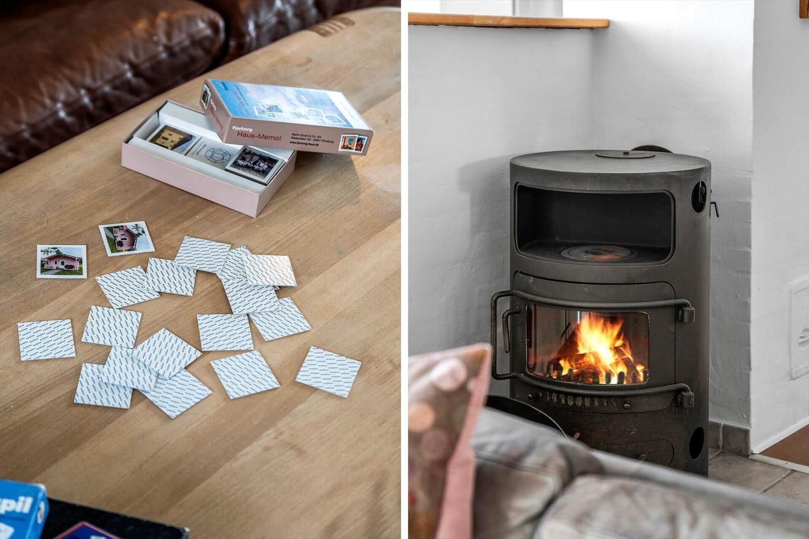Holztisch mit Spielkarten und Kaminofen mit brennendem Feuer.