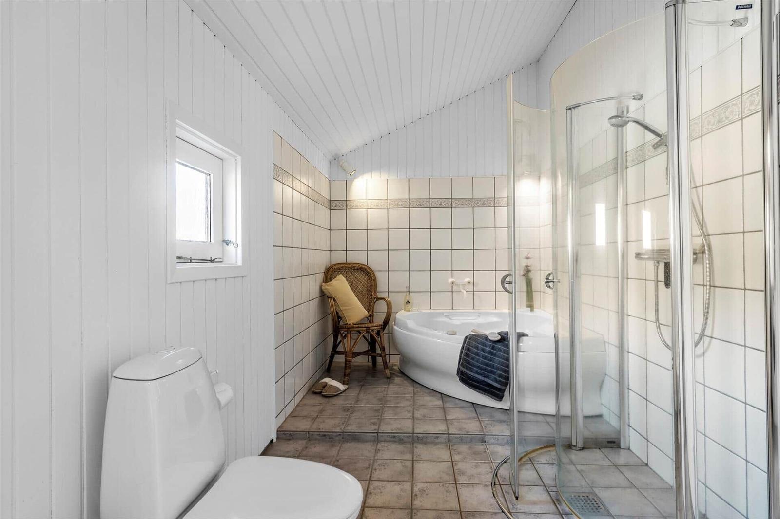 Badezimmer mit Dusche, Badewanne und Toilette. Weiße Wände und Fliesen.