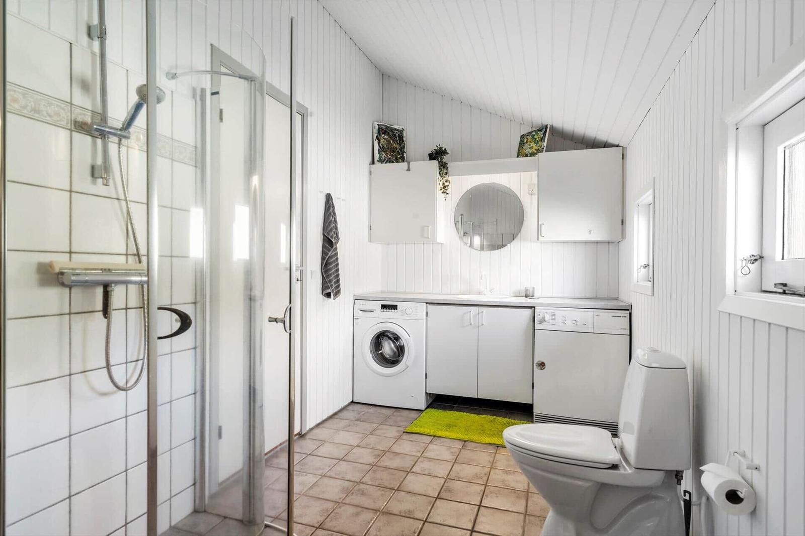Badezimmer mit Dusche, Waschmaschine, Spülmaschine und Toilette.