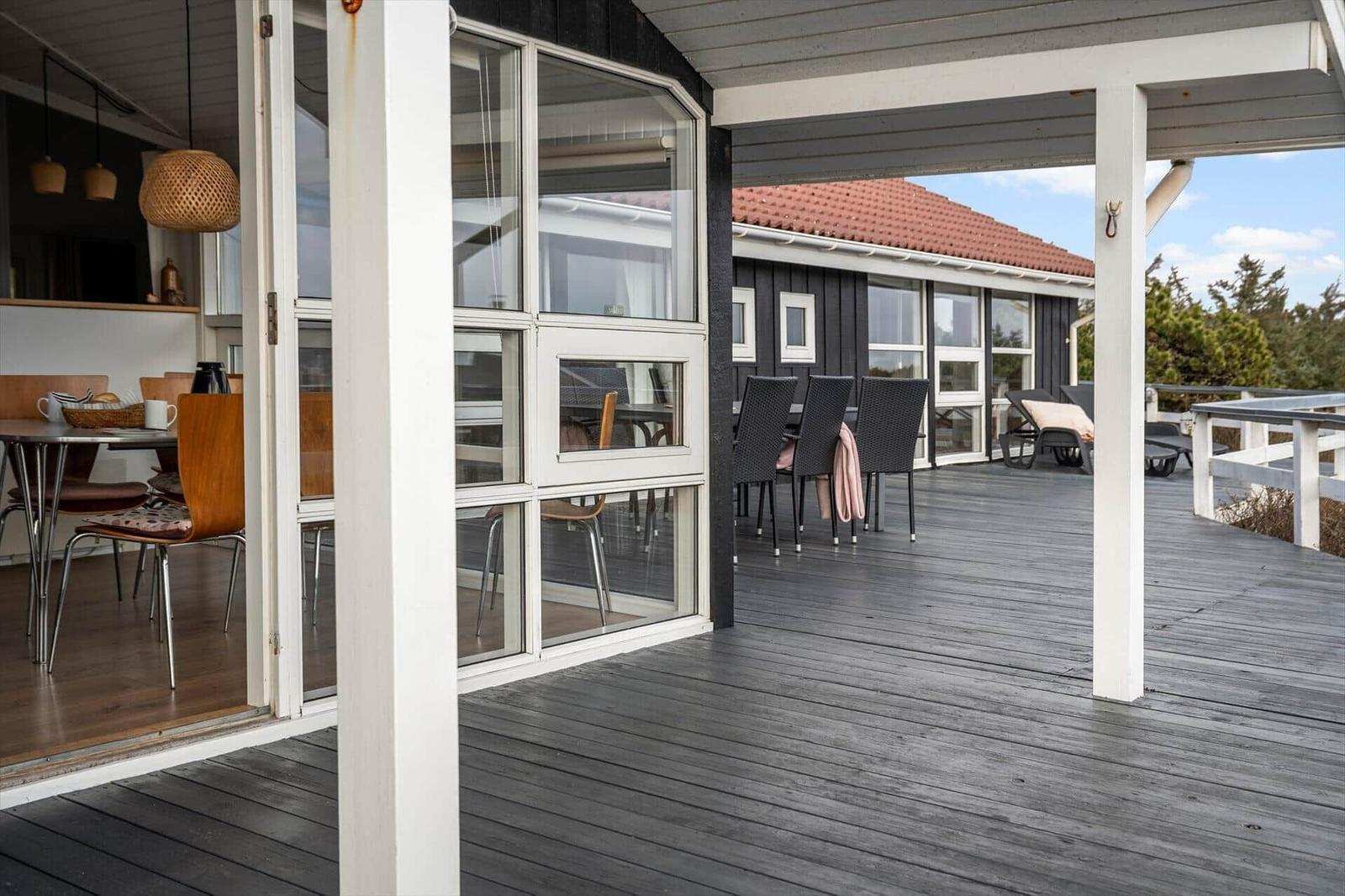 Terrasse mit Sitzgelegenheiten und Blick auf Haus mit rotem Dach.