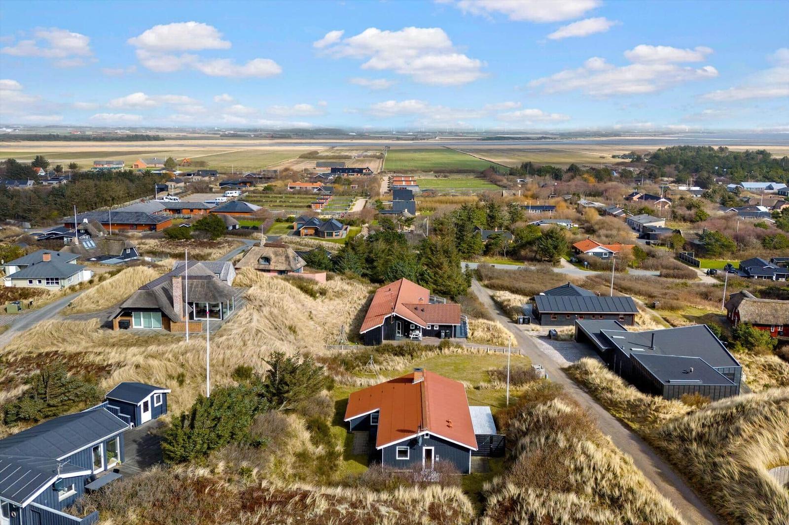 Luftbild von Ferienhäusern auf Hügeln mit Blick auf Felder und Horizont.